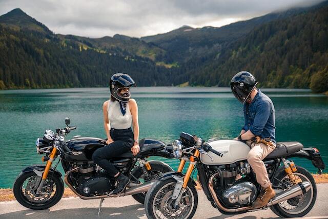 Young couple on motorcycles near a mountain lake