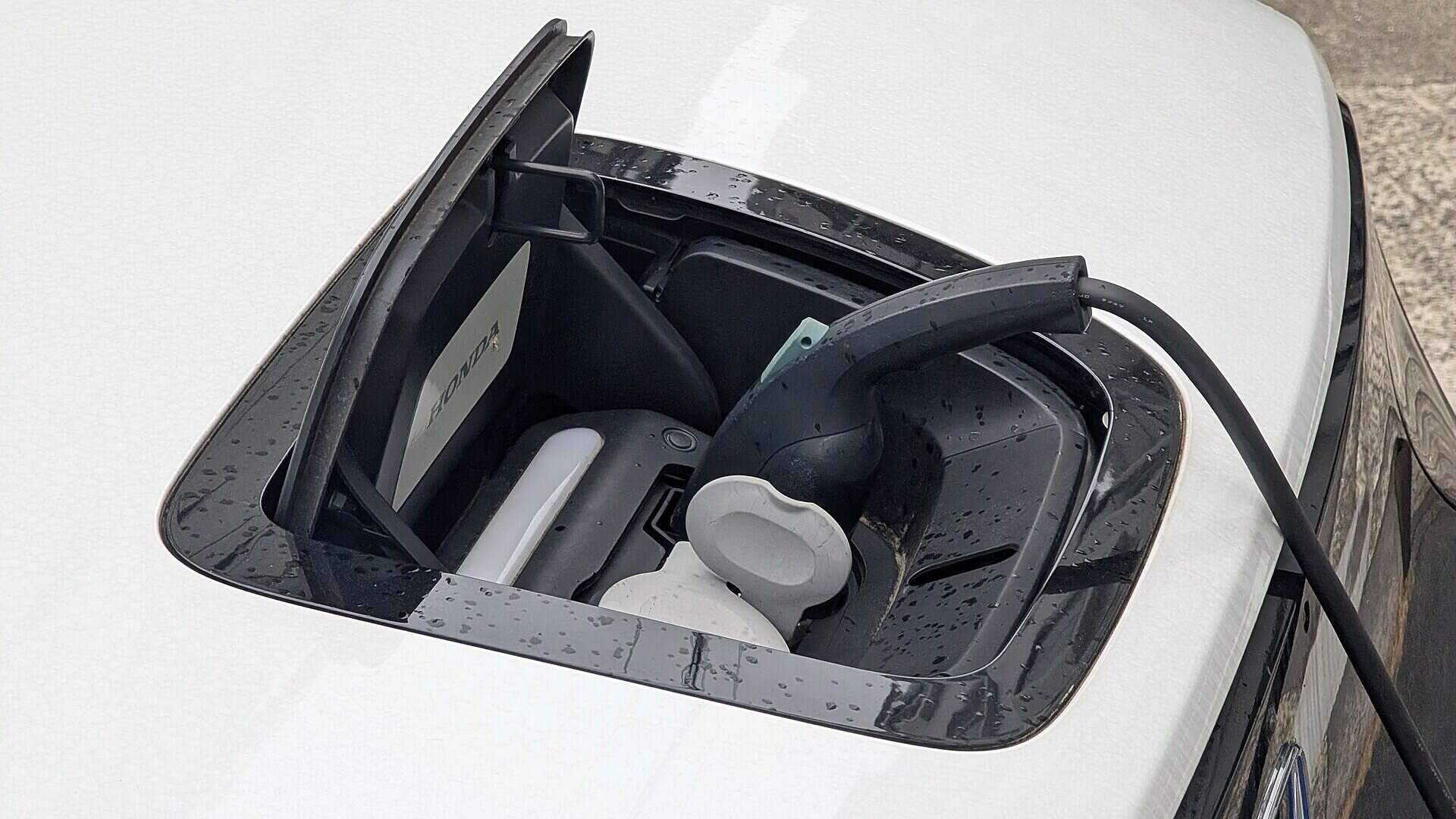 Toma de carga de un coche eléctrico blanco con el cable conectado