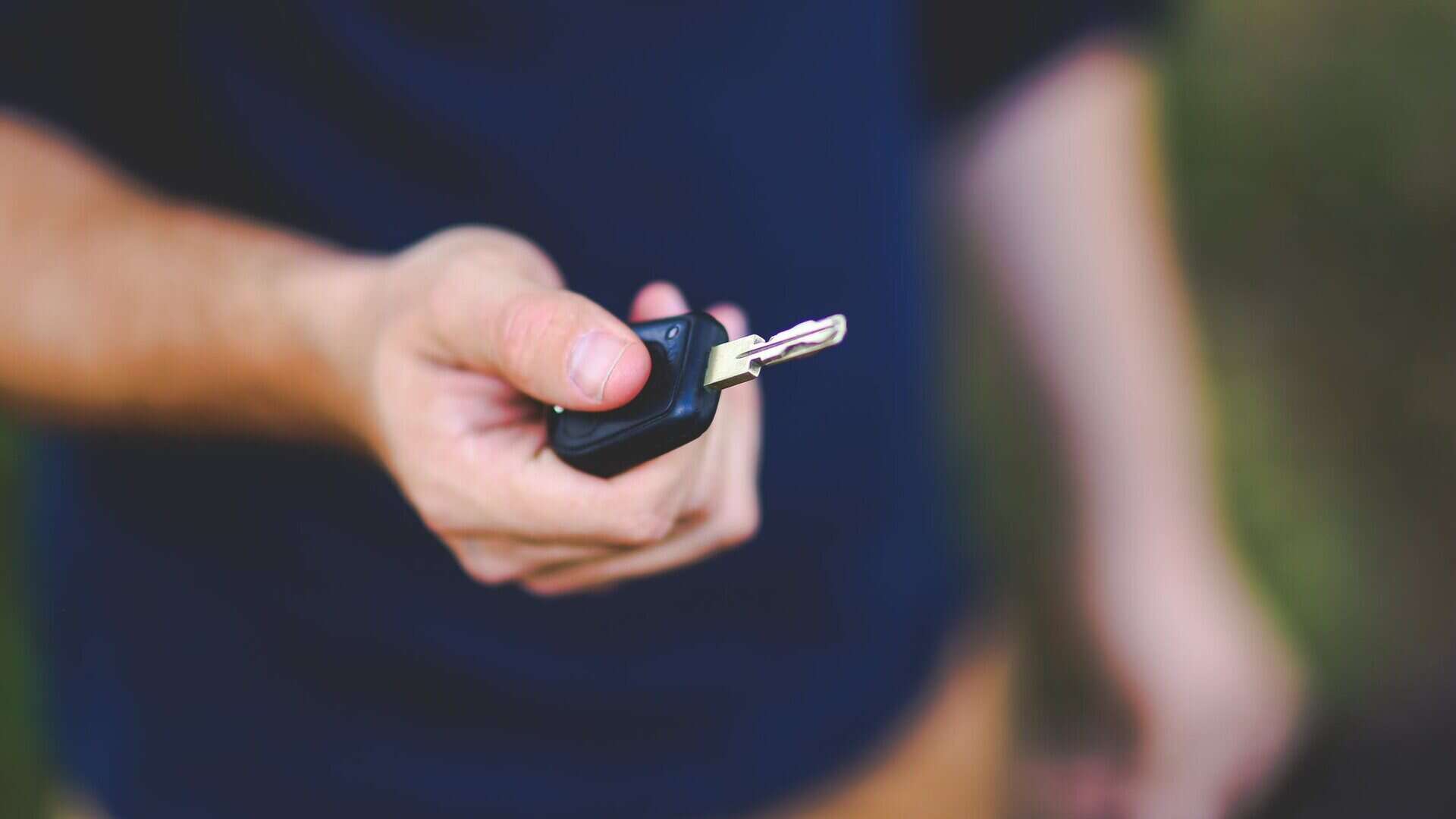 Hand, die einen Autoschlüssel überreicht
