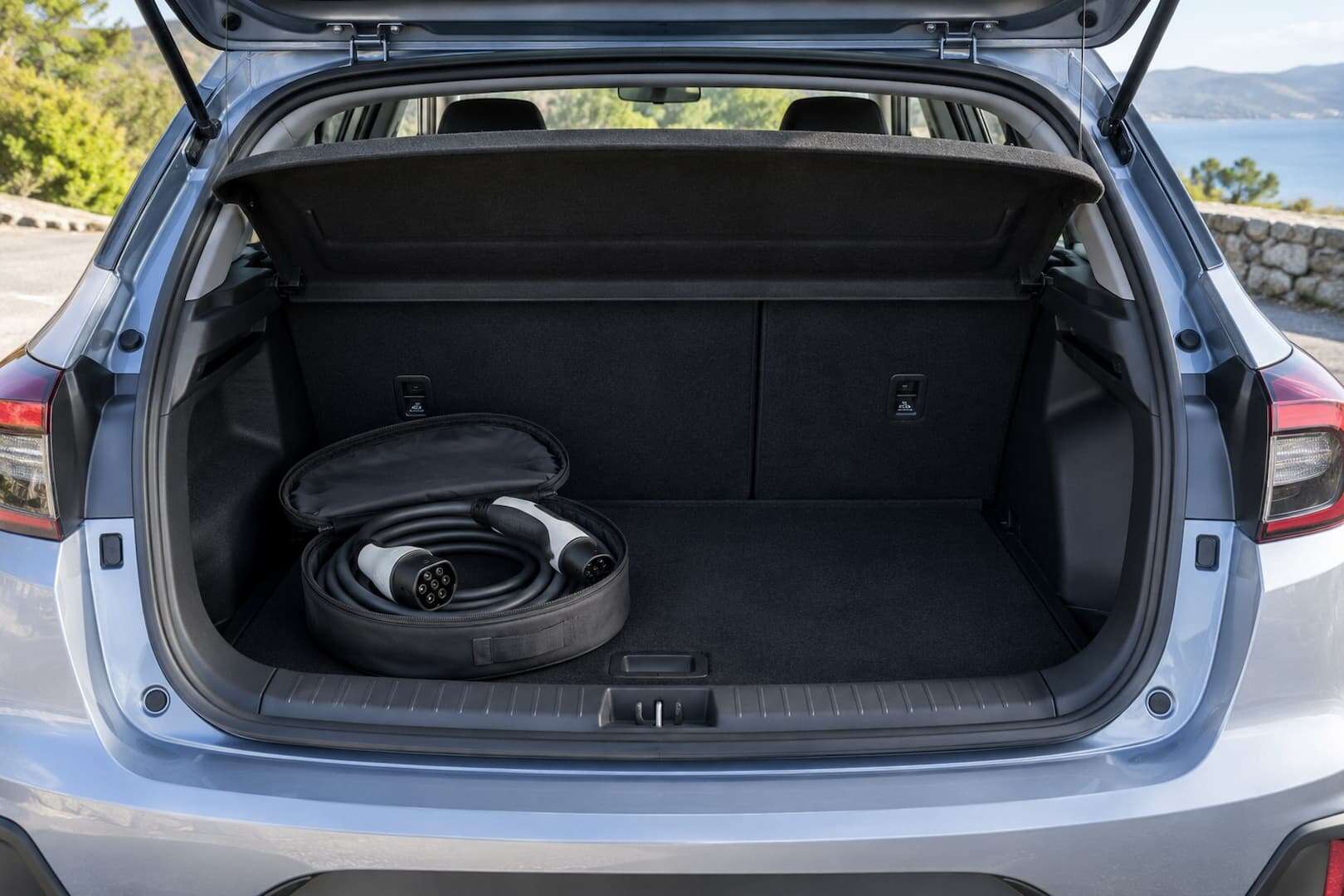 A clean electric rental car with its charging cable neatly stored in the boot