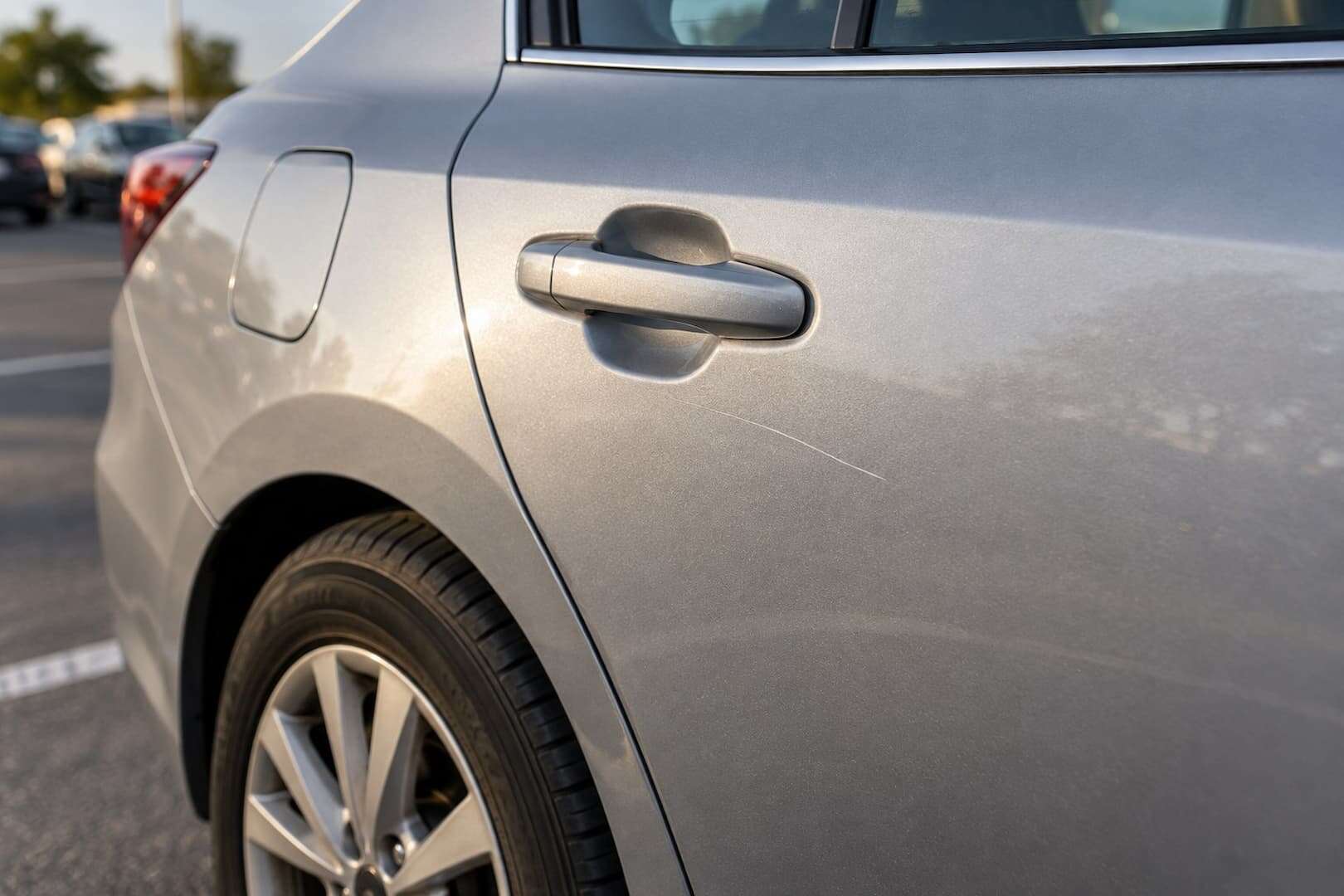A small existing scratch on the rear door of a rental car